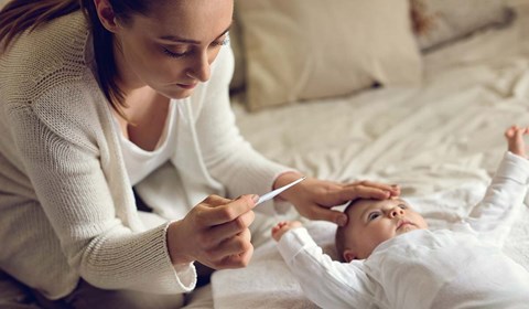 bekymret mor med baby og febermåler. 