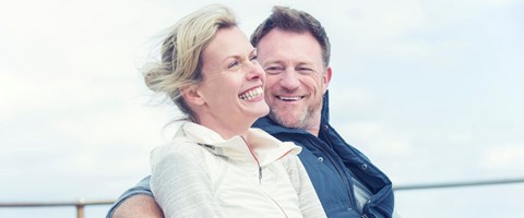 mann som ser forelsket bort på en leende kvinne, sittende på en strand. foto. 