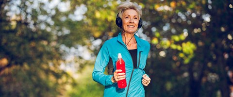 middelaldrende kvinne jogger fornøyd med en drikkeflaske i hånden. høstlig bakgrunn. 